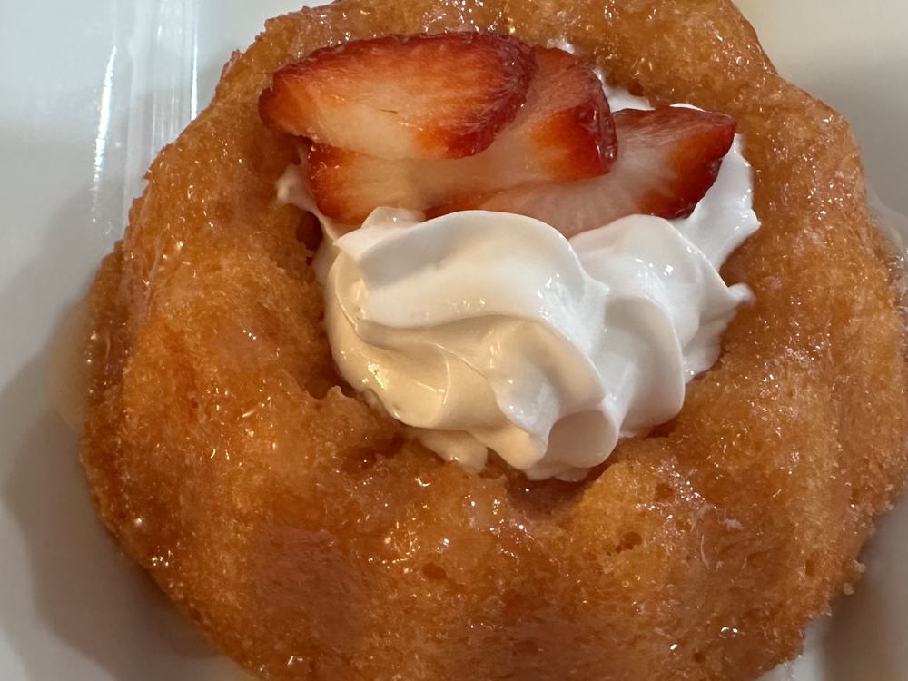 A glazed bundt cake topped with strawberries and cream