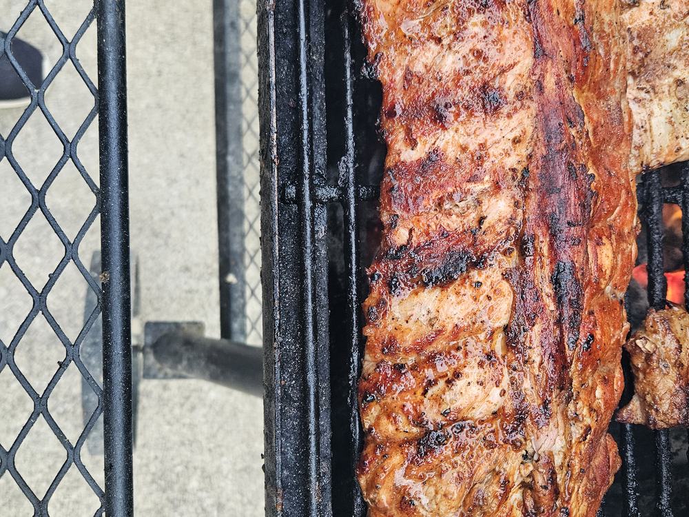 Racks of ribs cooking over a charcoal grill